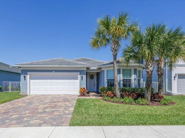 ranch-style home with stucco siding, decorative driveway, fence, a front yard, and a garage