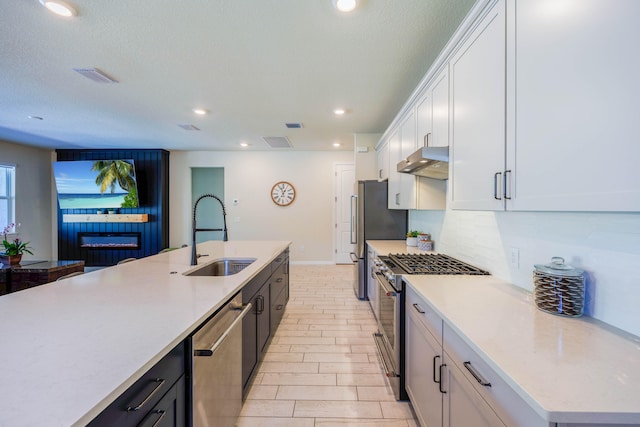 kitchen with visible vents, under cabinet range hood, light countertops, appliances with stainless steel finishes, and a sink