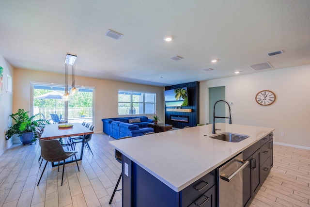 kitchen with a sink, light wood finished floors, stainless steel dishwasher, and light countertops