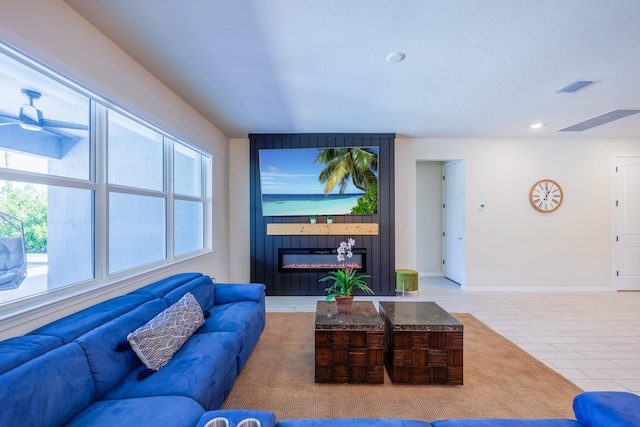 living area with visible vents, a large fireplace, tile patterned flooring, baseboards, and ceiling fan