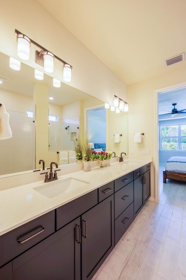 ensuite bathroom featuring a stall shower, wood finished floors, visible vents, and a sink