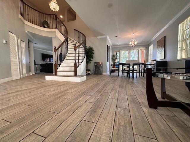 interior space featuring stairway, wood finished floors, crown molding, and a chandelier