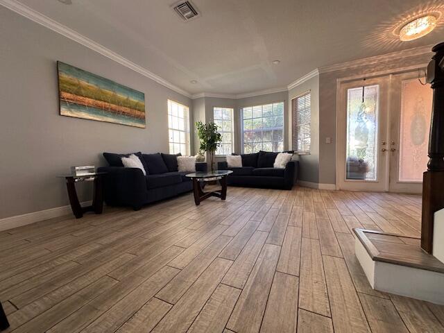 living area featuring crown molding, wood finished floors, visible vents, and baseboards