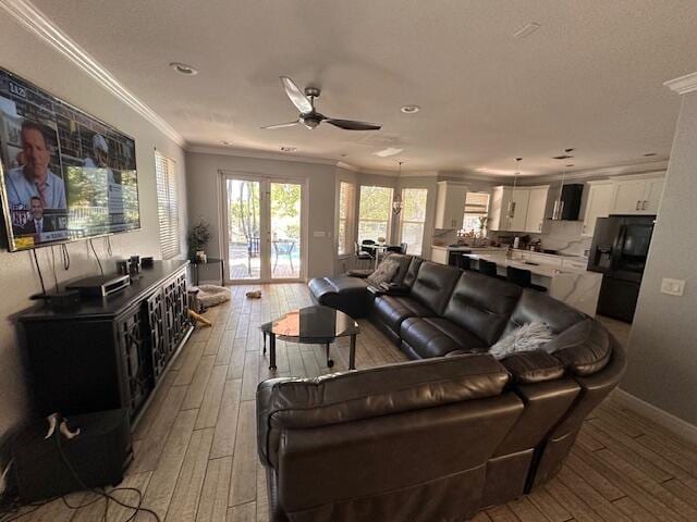 living room with french doors, light wood-style floors, ceiling fan, and crown molding