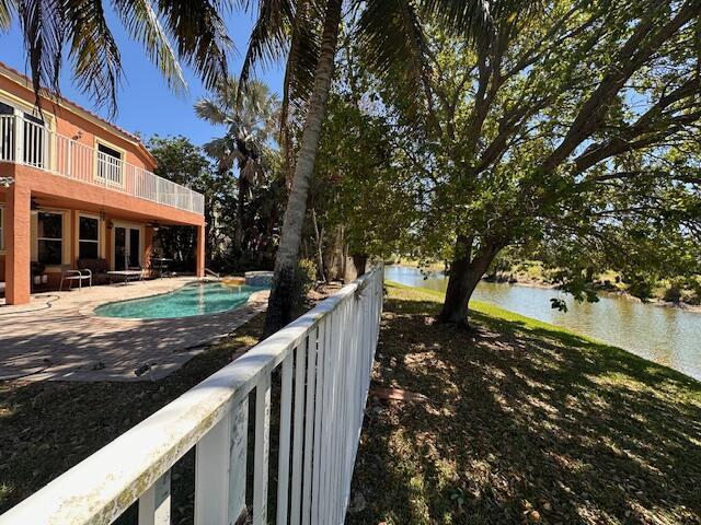 outdoor pool featuring a patio area, a water view, and french doors