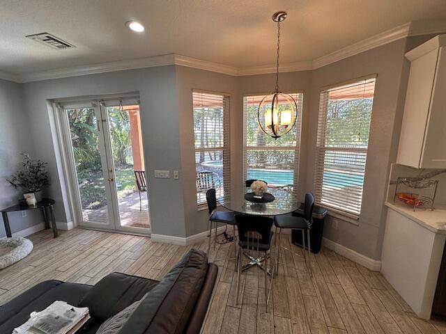 dining room featuring visible vents, a chandelier, crown molding, and light wood finished floors