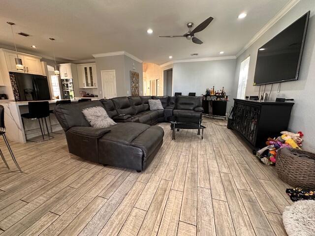 living area with recessed lighting, light wood-style floors, and ornamental molding