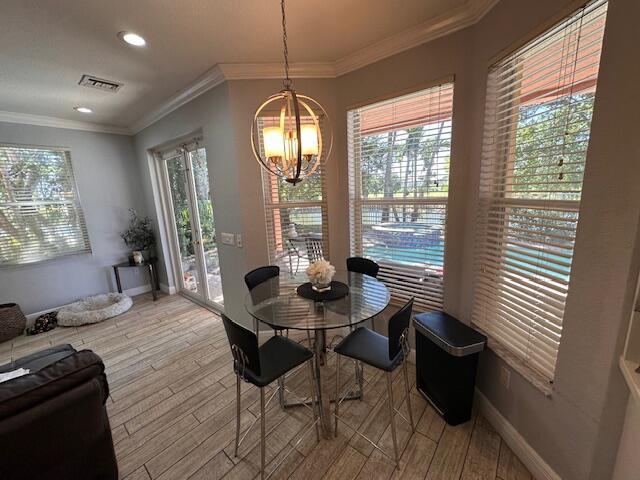 dining area featuring an inviting chandelier, light wood-style floors, baseboards, and ornamental molding