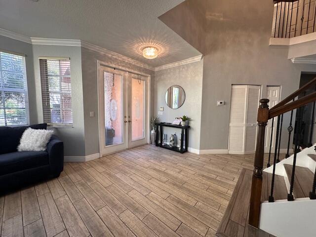 living area featuring crown molding, stairway, wood finished floors, and baseboards