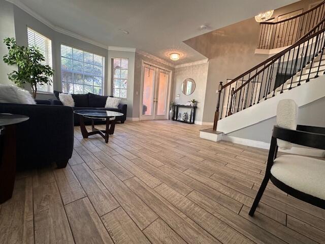 living room with stairway, baseboards, wood finished floors, and crown molding