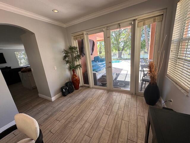 entryway featuring crown molding, baseboards, recessed lighting, wood finished floors, and arched walkways