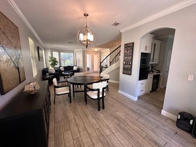 dining area featuring visible vents, stairway, light wood-style flooring, and ornamental molding