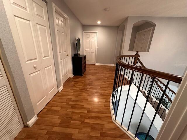 corridor with recessed lighting, an upstairs landing, wood finished floors, and baseboards