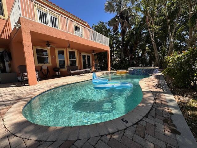 view of pool with a patio area, a pool with connected hot tub, and a ceiling fan