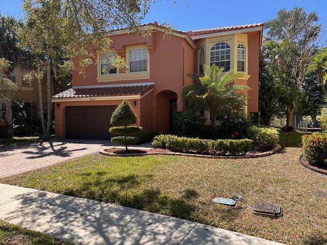 mediterranean / spanish house featuring a tiled roof, decorative driveway, a garage, and stucco siding