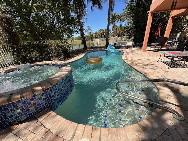 view of swimming pool featuring a fenced backyard, a pool with connected hot tub, and a patio