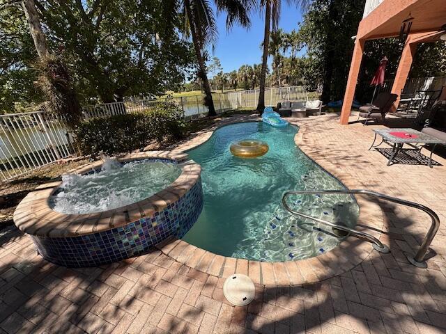 view of swimming pool with a pool with connected hot tub, a fenced backyard, and a patio area