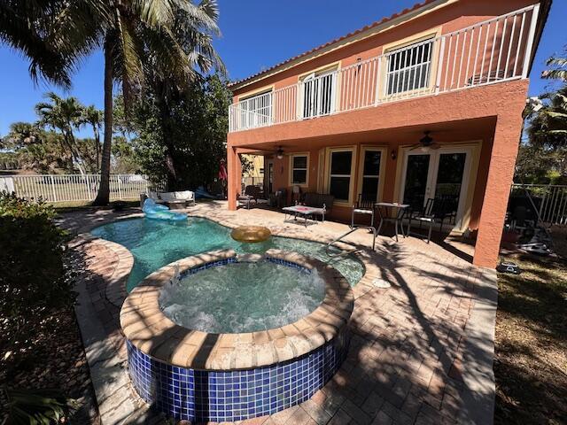 back of house featuring a patio, a balcony, a ceiling fan, a fenced backyard, and french doors