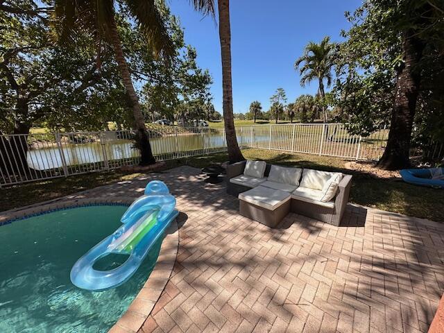 exterior space with a water view, a fenced backyard, and outdoor lounge area