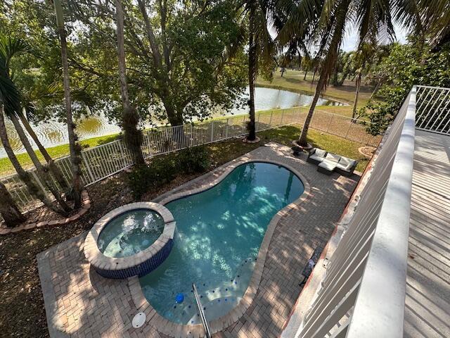 view of pool featuring a pool with connected hot tub, a fenced backyard, and a water view