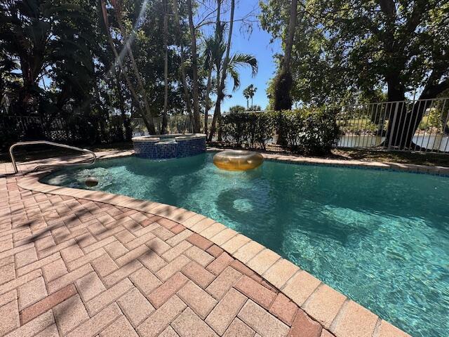 view of pool with a patio area, a pool with connected hot tub, and fence