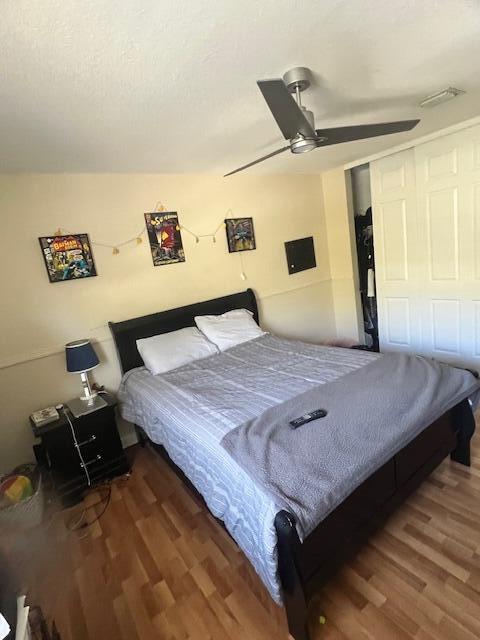 bedroom featuring a closet, a textured ceiling, a ceiling fan, and wood finished floors