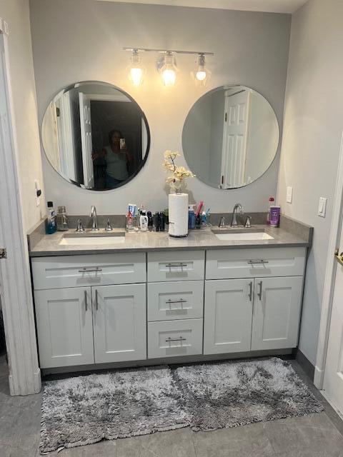 full bath featuring double vanity, baseboards, and a sink