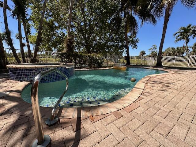 view of swimming pool featuring a pool with connected hot tub, a ceiling fan, a patio, and fence