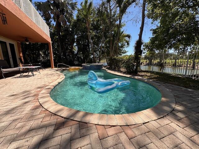 view of pool featuring ceiling fan, a pool with connected hot tub, a patio, and fence