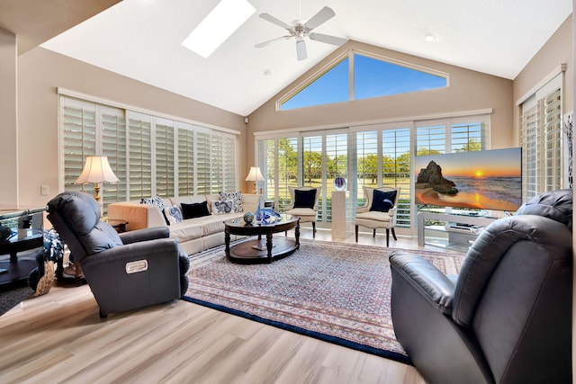 living area featuring a skylight, high vaulted ceiling, wood finished floors, and a ceiling fan