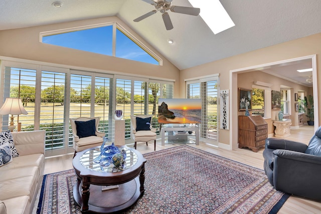 living area with a skylight, wood finished floors, high vaulted ceiling, and ceiling fan