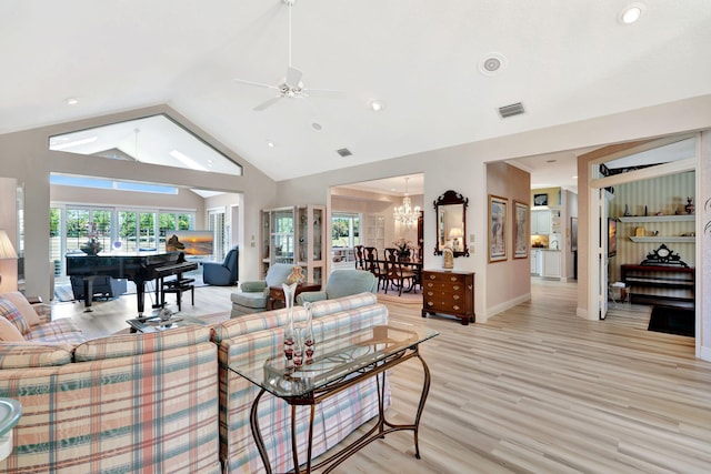 living room featuring visible vents, high vaulted ceiling, ceiling fan with notable chandelier, light wood finished floors, and baseboards