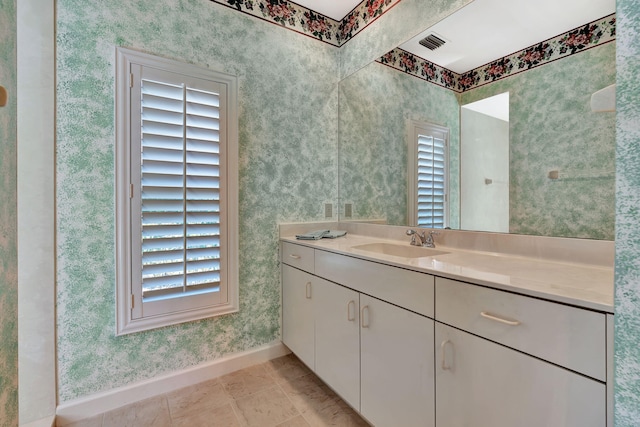 bathroom with wallpapered walls, baseboards, visible vents, and a healthy amount of sunlight