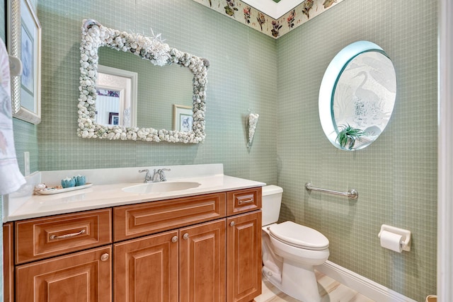 bathroom with vanity, toilet, and wallpapered walls