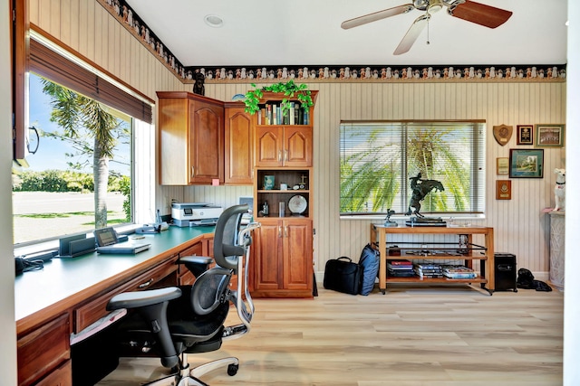 office with light wood-style flooring, a ceiling fan, and wood walls