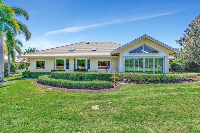 back of property with a tiled roof, a yard, and stucco siding