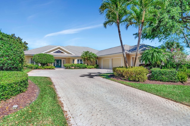 ranch-style house featuring stucco siding, an attached garage, and decorative driveway