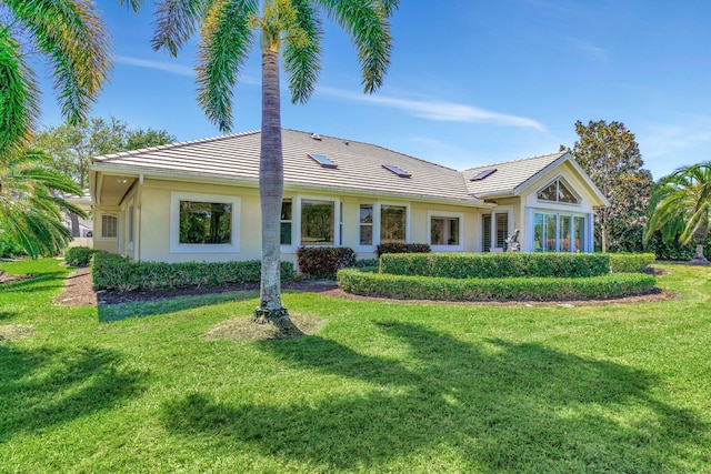 back of property with a lawn, a tiled roof, and stucco siding