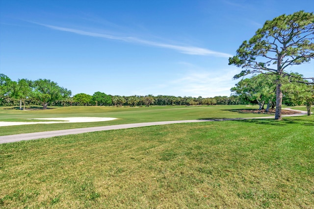 view of property's community featuring view of golf course and a yard