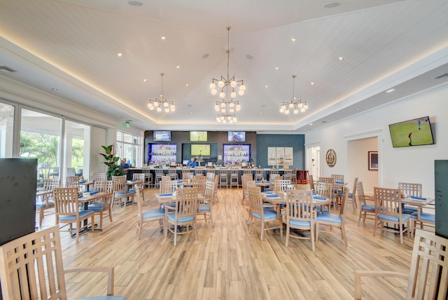 dining area featuring visible vents, high vaulted ceiling, a tray ceiling, light wood finished floors, and a chandelier