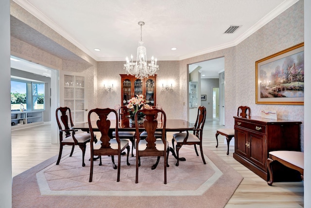 dining space featuring light wood finished floors, visible vents, wallpapered walls, ornamental molding, and a notable chandelier