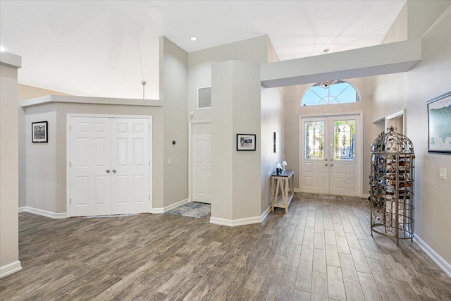 entrance foyer featuring visible vents, a towering ceiling, baseboards, and wood finished floors