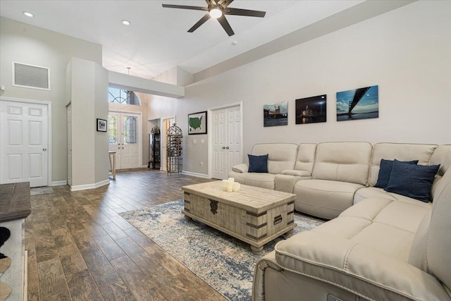 living area with dark wood-style floors, visible vents, a ceiling fan, and baseboards