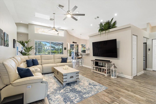 living room with baseboards, wood finished floors, visible vents, and high vaulted ceiling