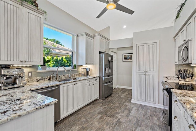 kitchen featuring light stone counters, dark wood-style floors, a sink, appliances with stainless steel finishes, and tasteful backsplash