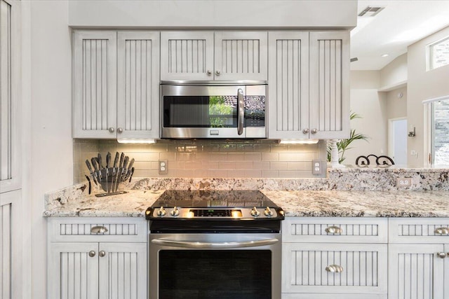 kitchen with tasteful backsplash, light stone countertops, visible vents, and appliances with stainless steel finishes