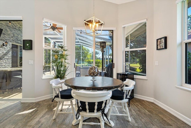 dining area with a chandelier, a sunroom, baseboards, and dark wood-style flooring