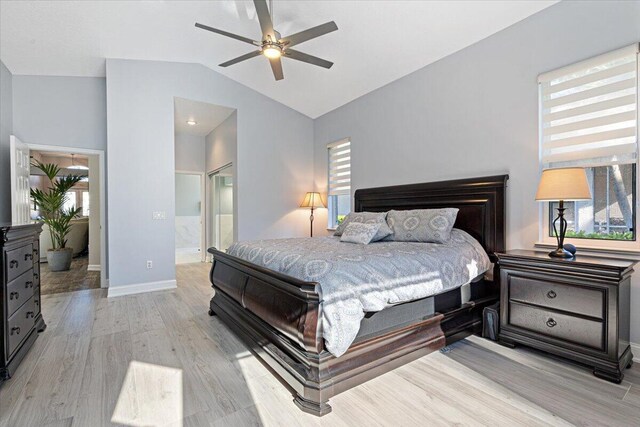 bedroom with light wood-type flooring, baseboards, connected bathroom, and vaulted ceiling