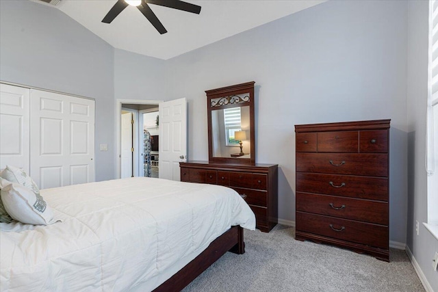 bedroom with a ceiling fan, baseboards, vaulted ceiling, a closet, and light colored carpet