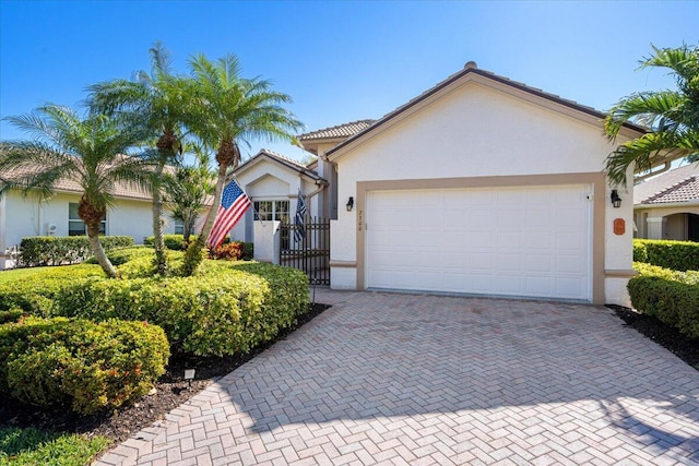 view of front of home with stucco siding, a gate, decorative driveway, a garage, and a tiled roof